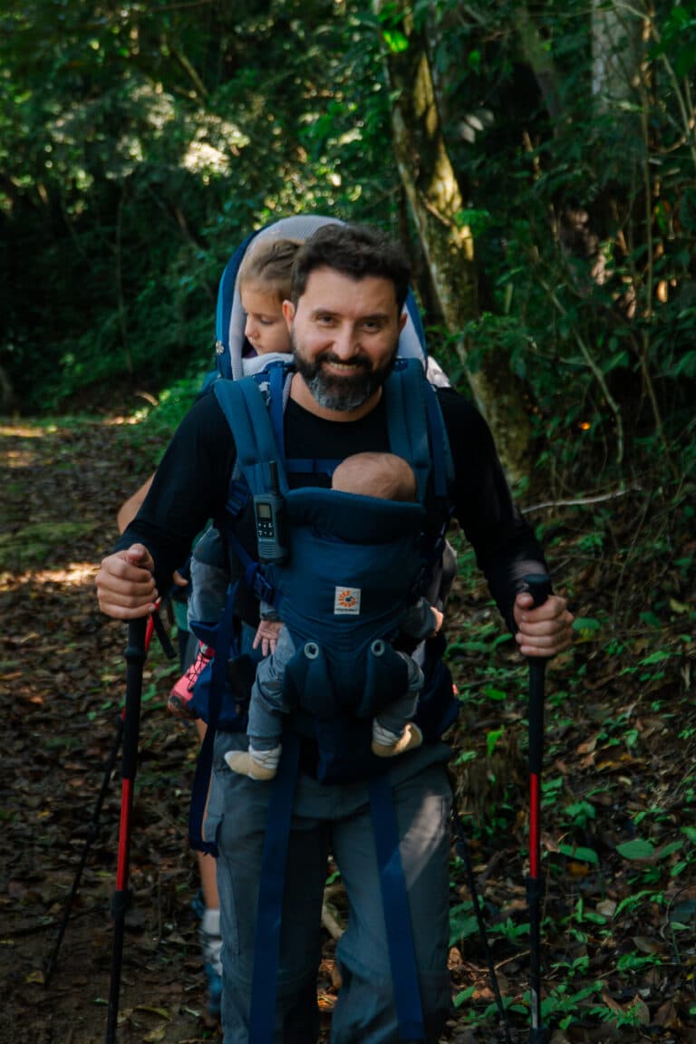 Homem carregando 2 filhos em um trilha