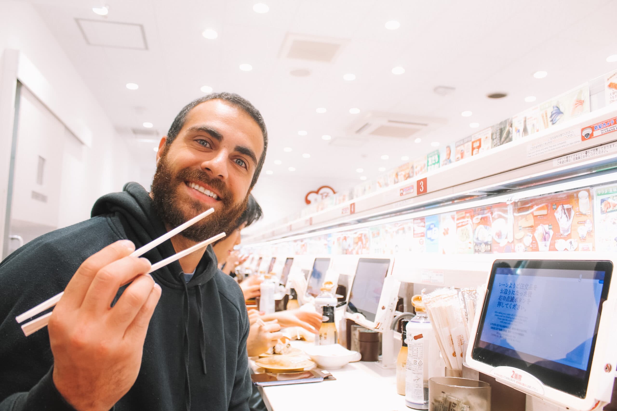 Homem sentado a mesa segurando um hashi