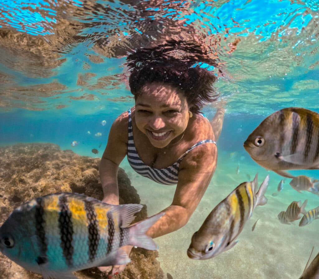 Mulher embaixo d'agua nadando com peixes