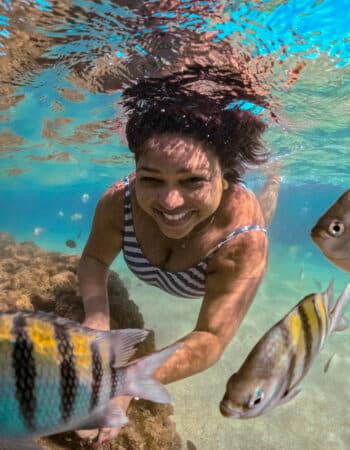 Mulher embaixo d'agua nadando com peixes