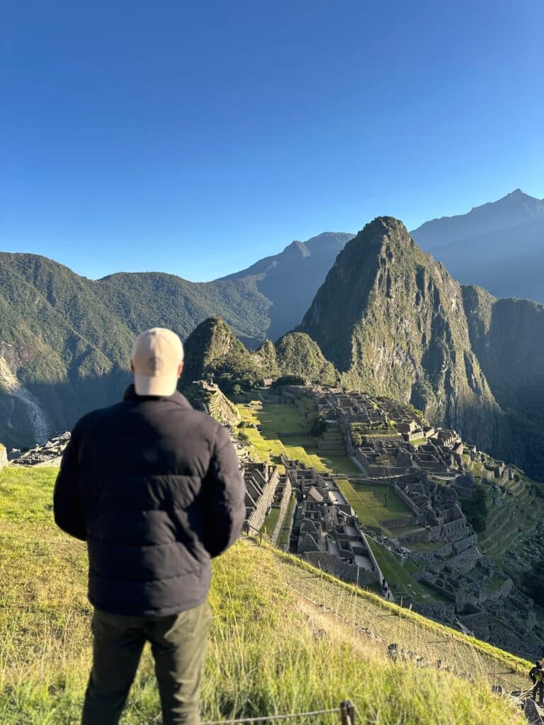 Homem responsável pelo perfil de Instagram Localizando Checkin em frente a uma montanha em Machu Picchu