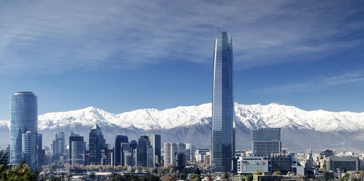 Vista panorâmica de Santiago do Chile com vários prédios, o sky costaneira e os andes