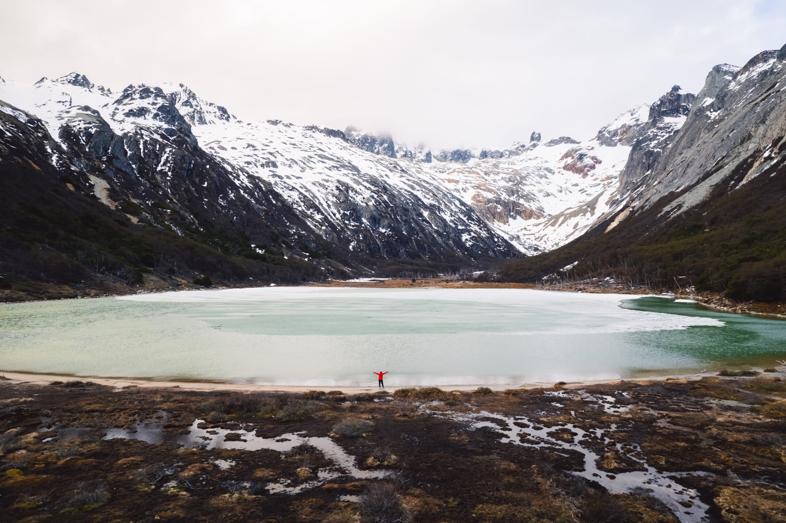 Montanhas cobertas de gelo em frente a um lago de águas frias e verdes em Ushuaia na Argentina