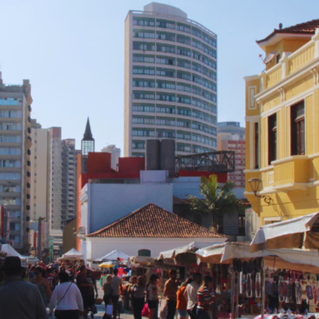 Feira artesanal em curitiba, com várias barracas na rua e muitas pessoas